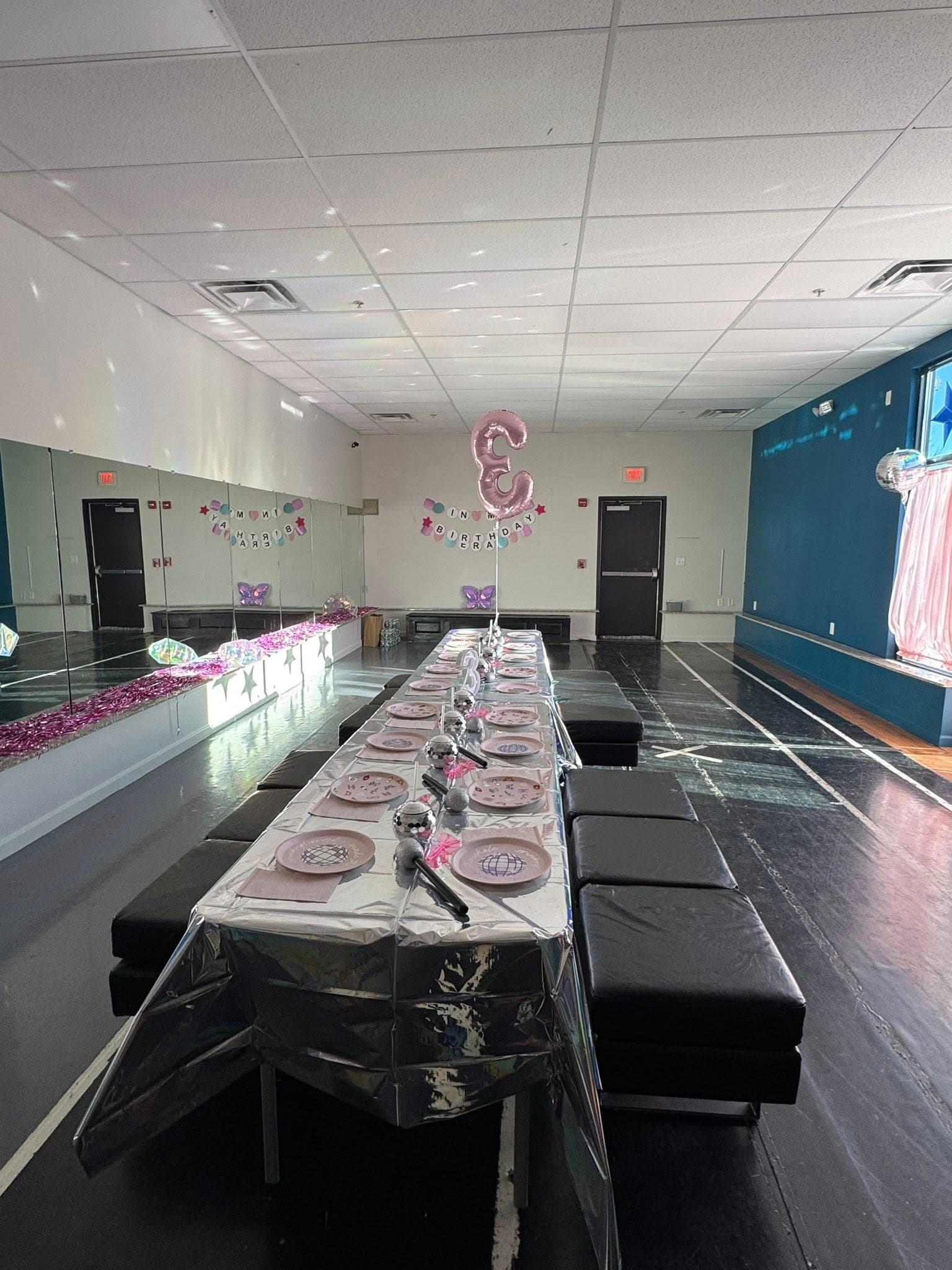 Birthday party table setup with pink plates and balloon decorations in the dance studio