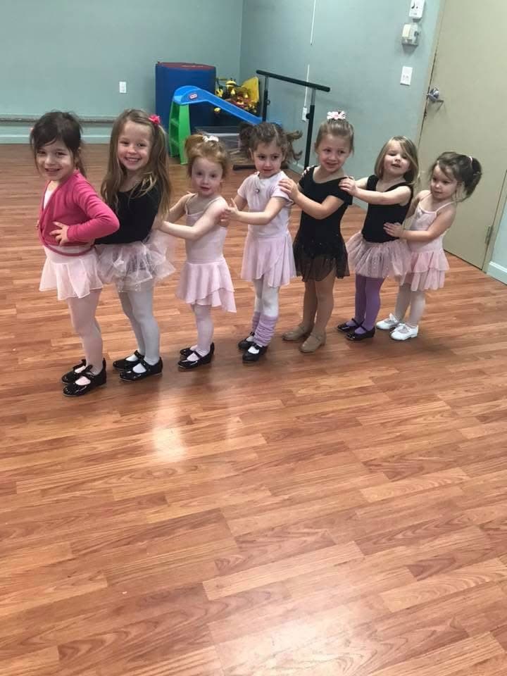 Young dancers in ballet outfits posing together in the studio