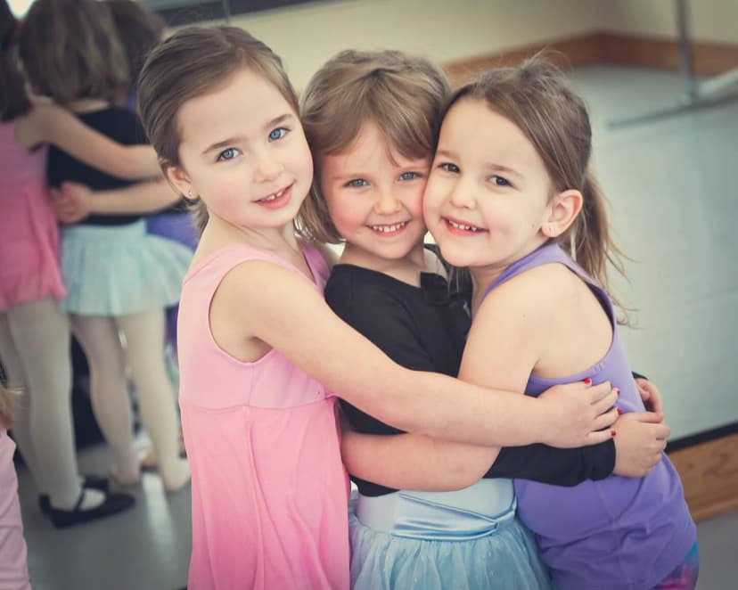 Three young dancers hugging and smiling